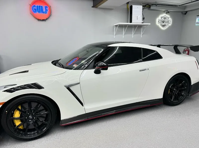 White Nissan GT-R Nismo in a home garage with fresh ceramic tint on the door glass.