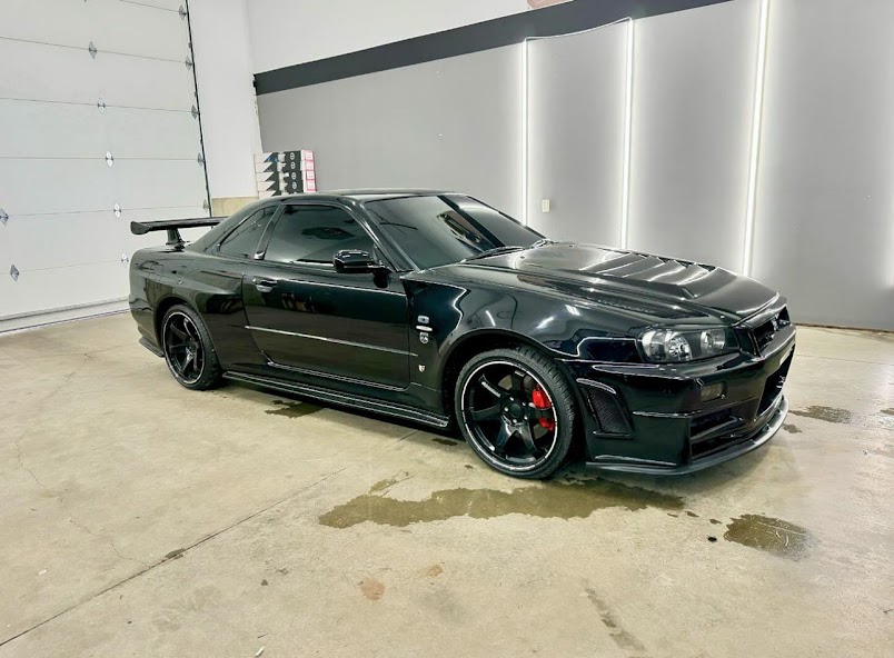 Nissan Skyline R34 GT-R wearing dark ceramic tint, photographed in the install bay.