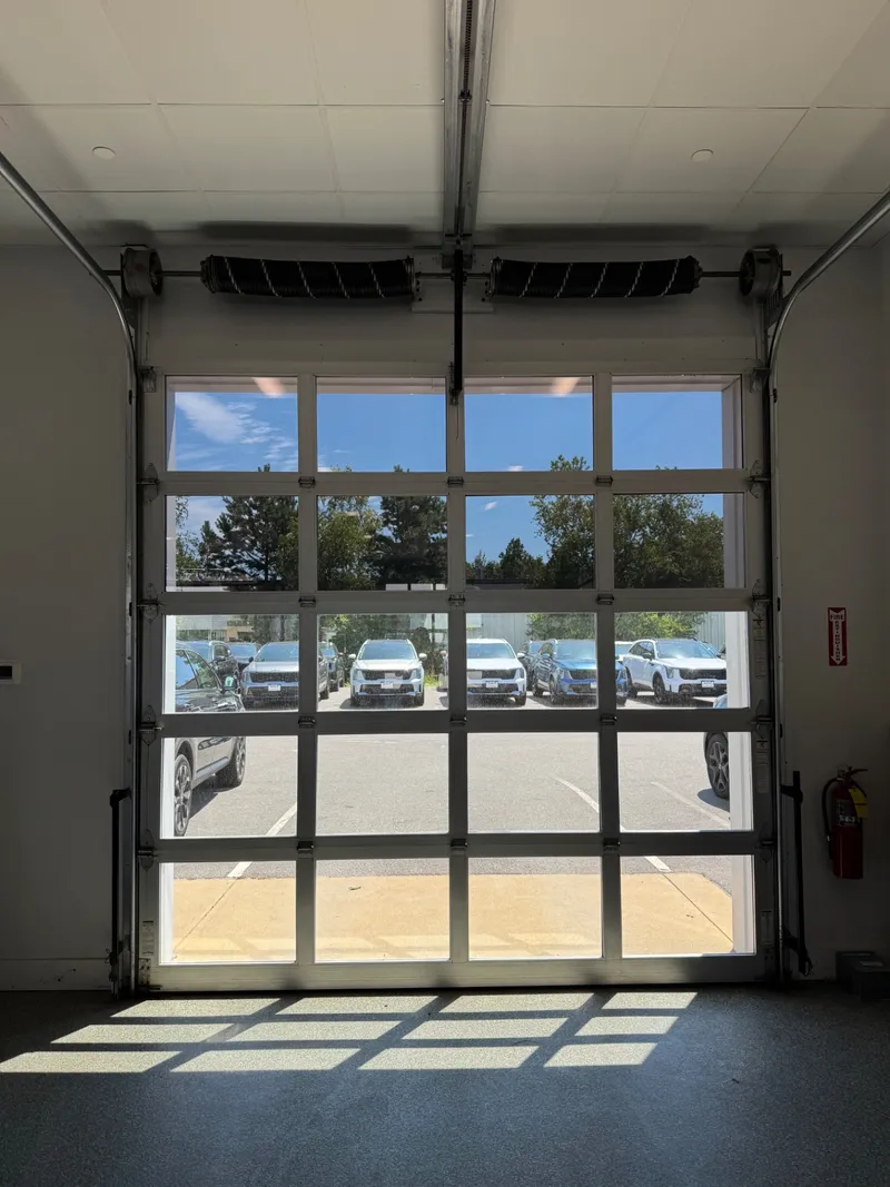 Glass overhead door with solar control film, looking out to the lot from inside the bay.