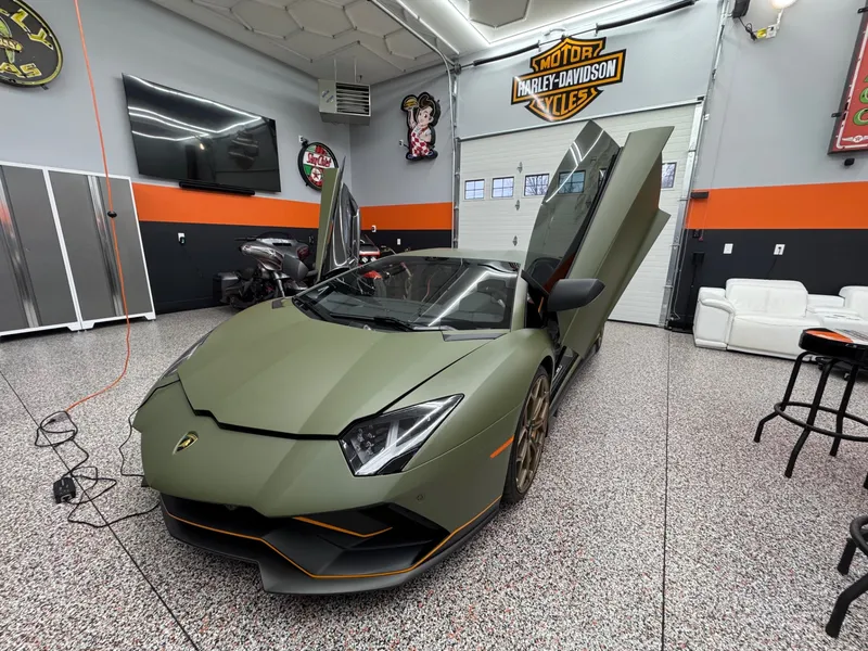 Aventador SVJ with scissor doors raised in the Epsom install bay after tinting.