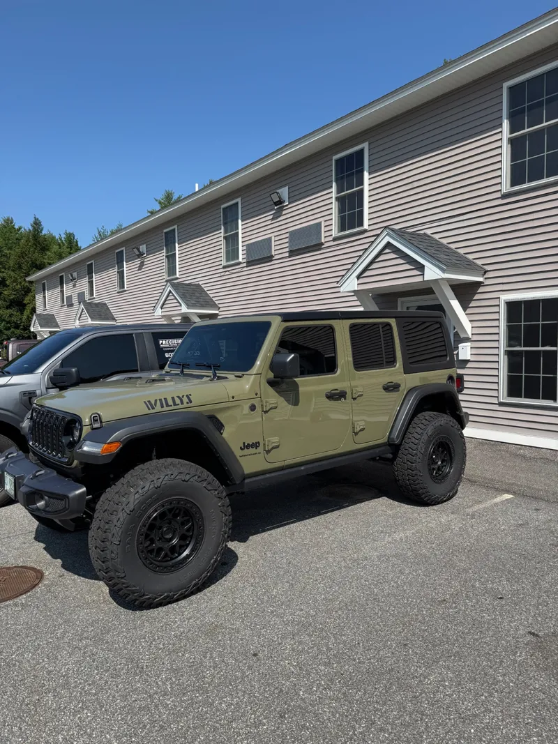 Olive green Jeep Wrangler Willys with tinted glass outside the Precision Films shop.