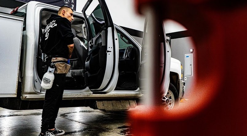 Precision Films installer squeegeeing film into a truck cab at the Epsom shop.