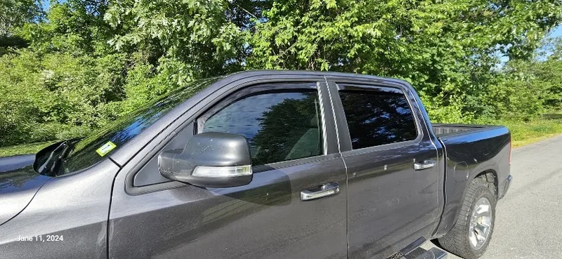 Ram 1500 crew cab with tinted door glass, shot outdoors on a bright summer afternoon.