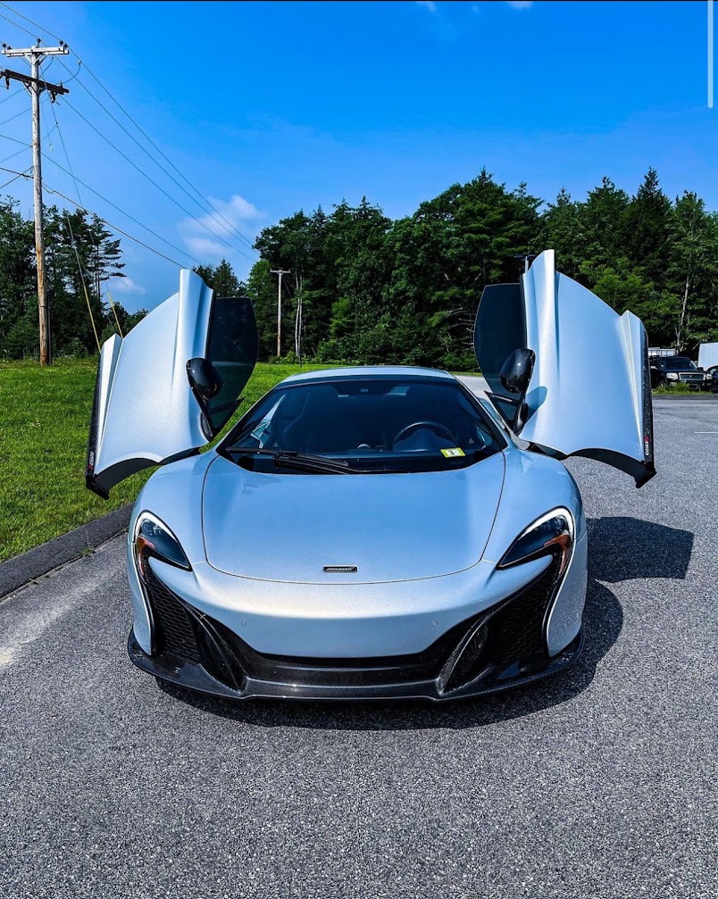 Silver McLaren with doors raised, side glass finished in high-heat-rejection film.