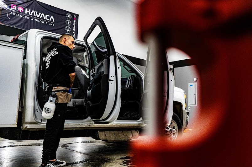 Precision Films installer squeegeeing film into a truck cab at the Epsom shop.