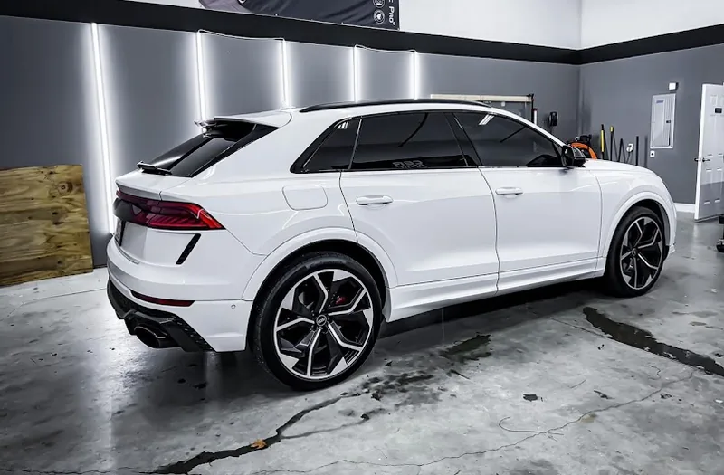 White Audi RS Q8 under bay lighting with dark ceramic film on the rear and side glass.