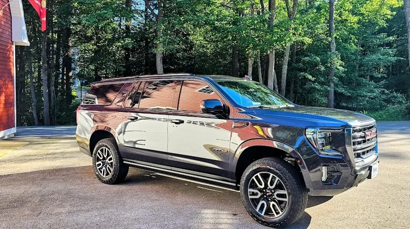 Three-quarter view of a tinted GMC Yukon XL showing even shade across every window.