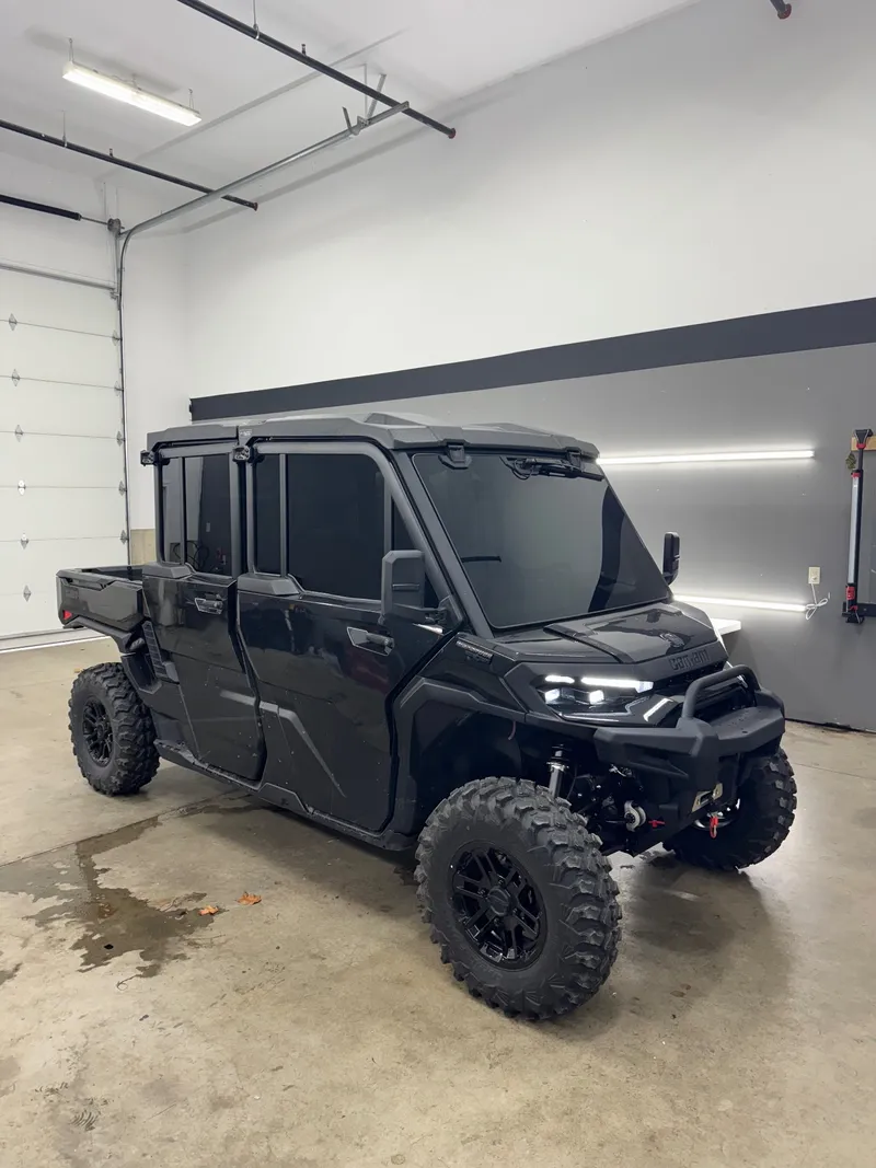 Black four-door Can-Am Defender in the shop with tinted cab glass all around.
