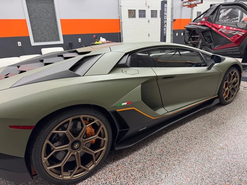 Rear three-quarter view of a green Aventador SVJ showing dark ceramic film on the glass.