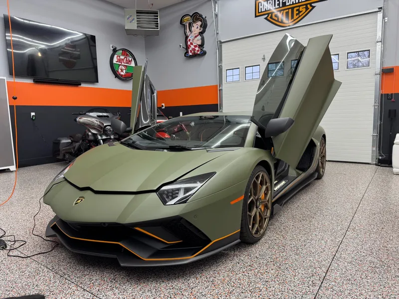 Green Lamborghini Aventador SVJ with doors up after a ceramic tint install in the shop.