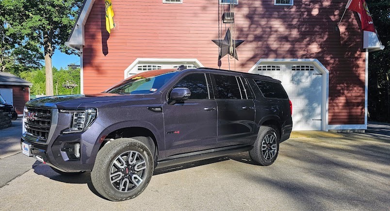 GMC Yukon parked at a New Hampshire home with all side glass tinted to match.